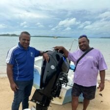 TSRA Chairperson George Nona with David Baragud and his new outboard motor on the beach near Thursday Island with sea in background.