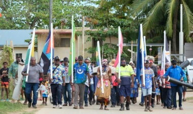 Community members from Saibai in the Torres Strait region proudly march with flags to celebrate their seasonal calendar launch.